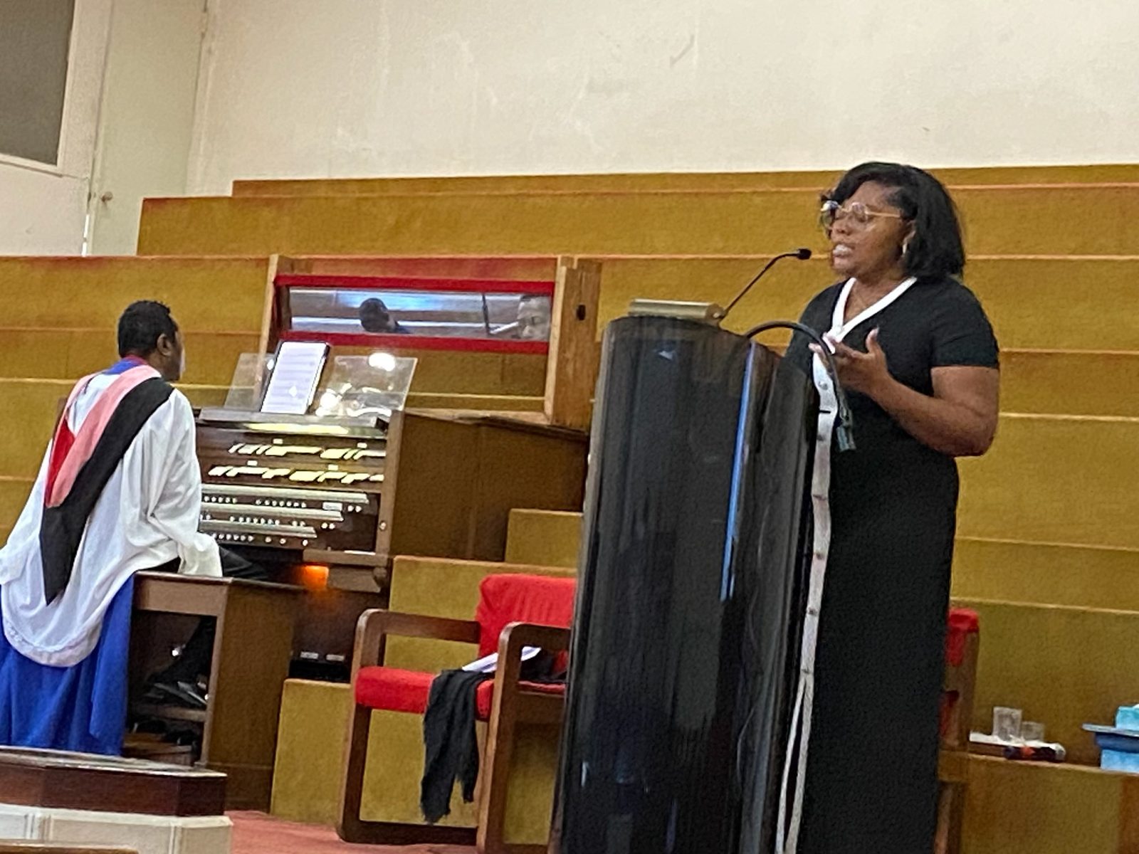Minister Shannon McLeod giving the message at the pulpit, beside the organist