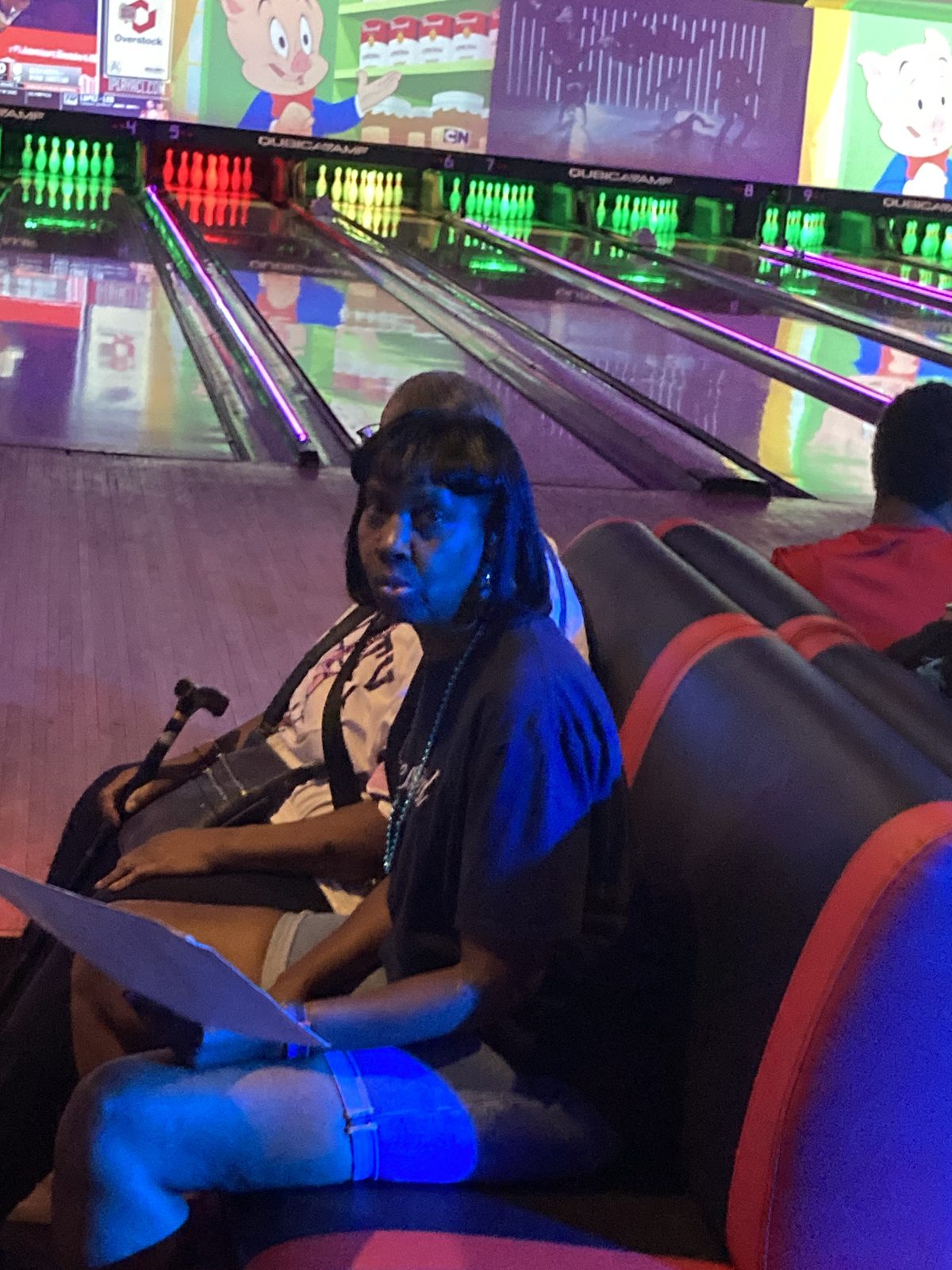 A woman seated beside the bowling lanes